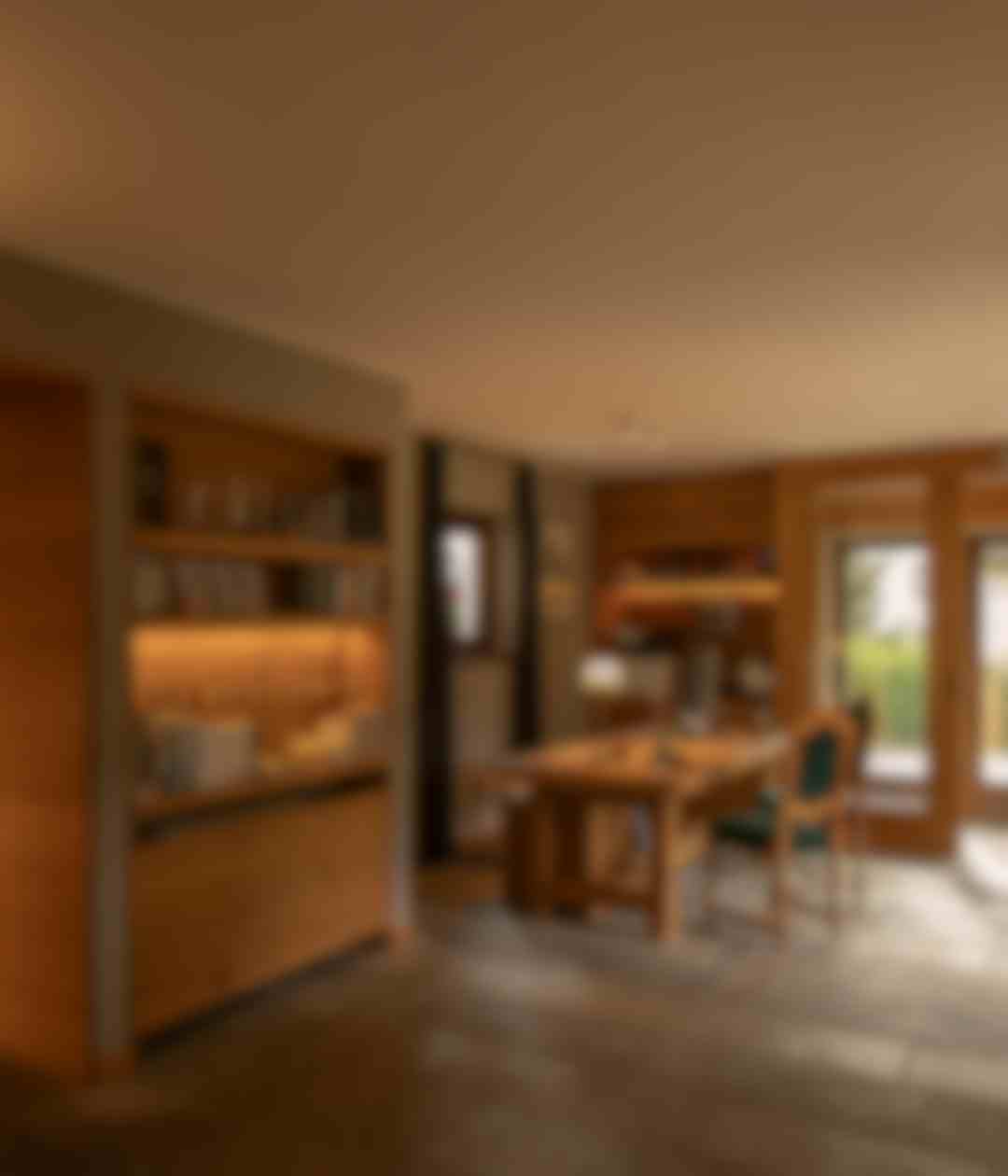 Zona pranzo interna con panca rivestita in velluto verde, libreria e vista sul soggiorno con ampie vetrate