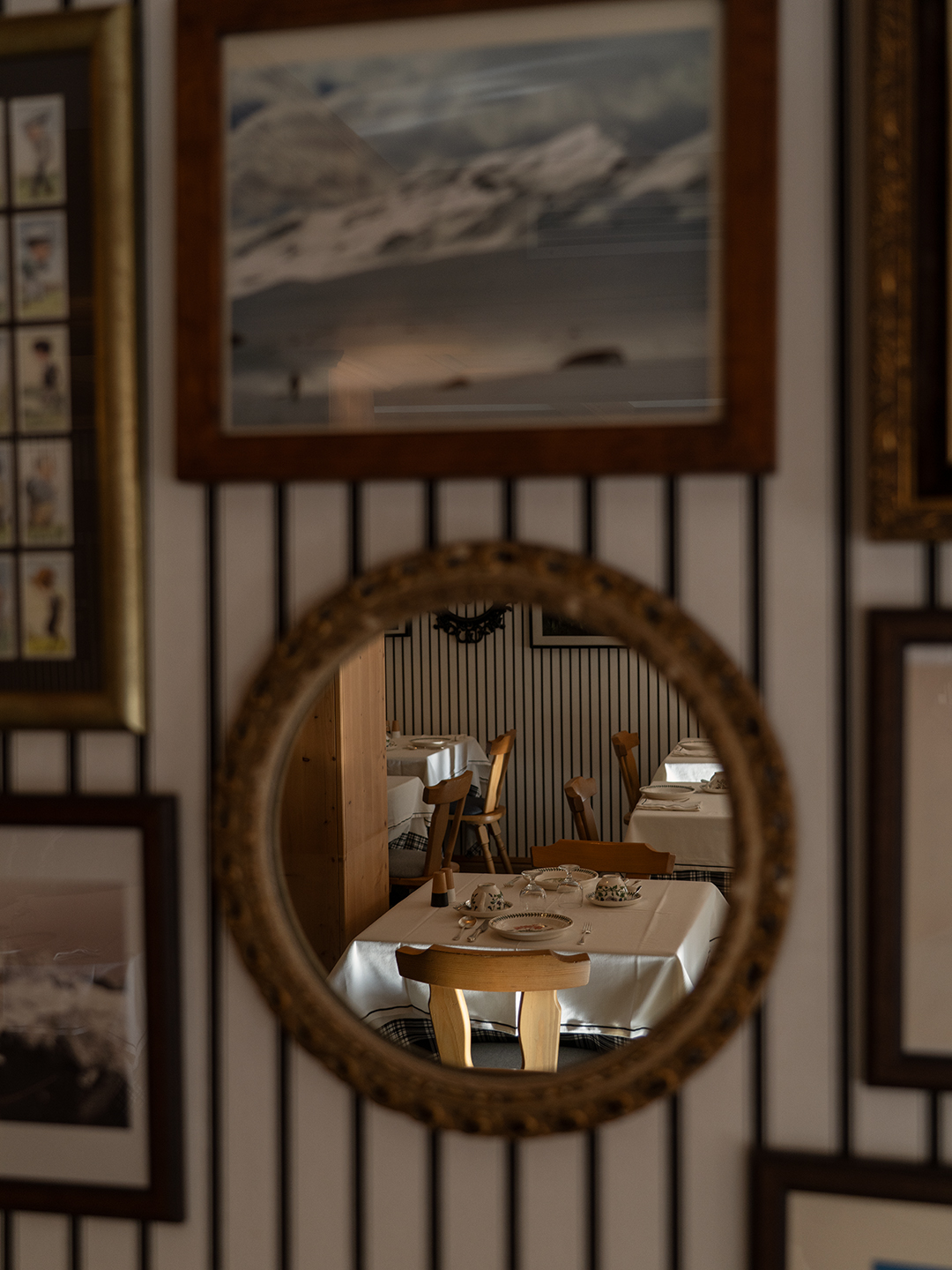 Sala ristorante dell'hotel vista attraverso specchio rotondo antico, tavoli apparecchiati con tovaglie bianche e sedie in legn