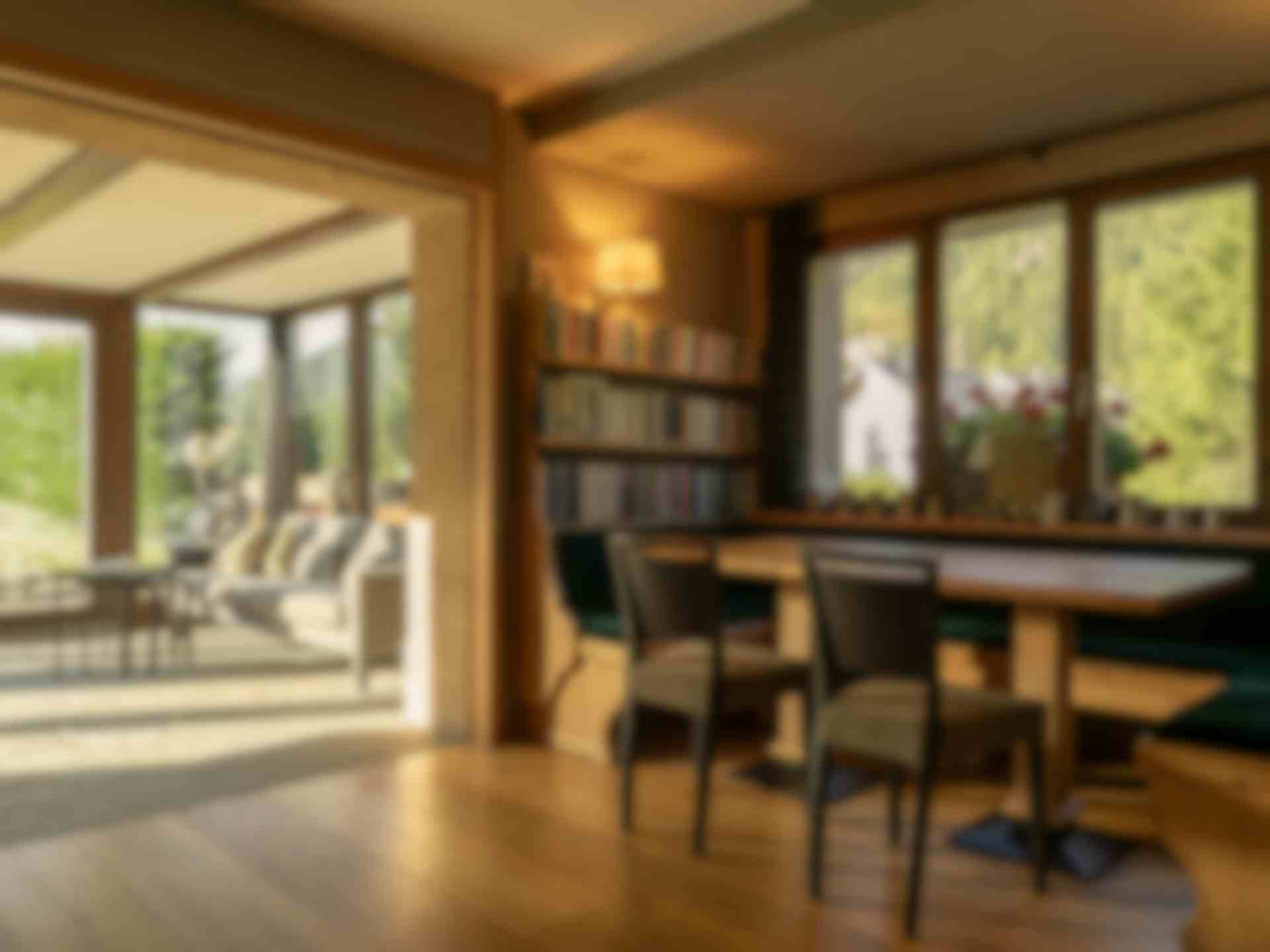 Zona salotto interna con panca rivestita in velluto verde, libreria e vista sul soggiorno con ampie vetrate