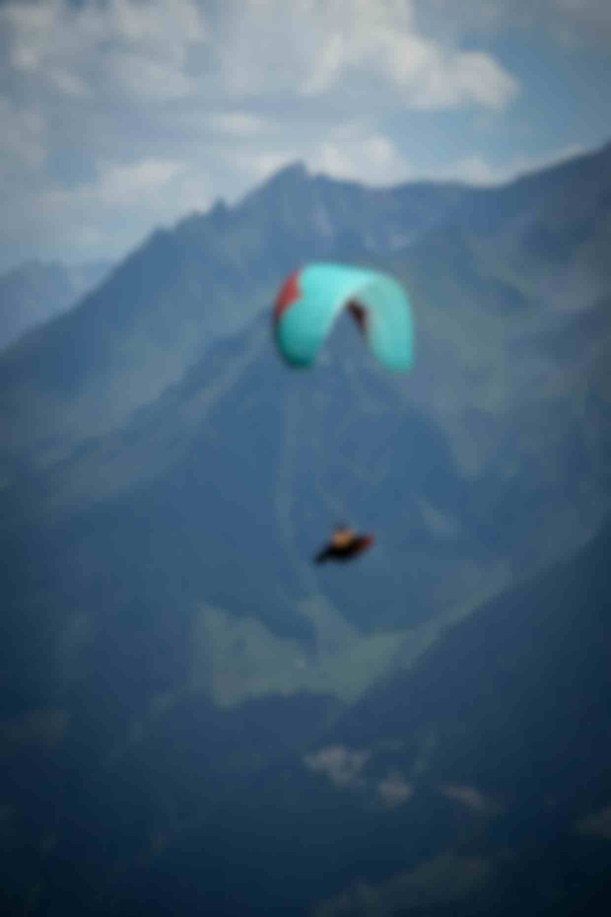 Parapendio con vela turchese in volo sopra le valli alpine, vista mozzafiato sulle montagne