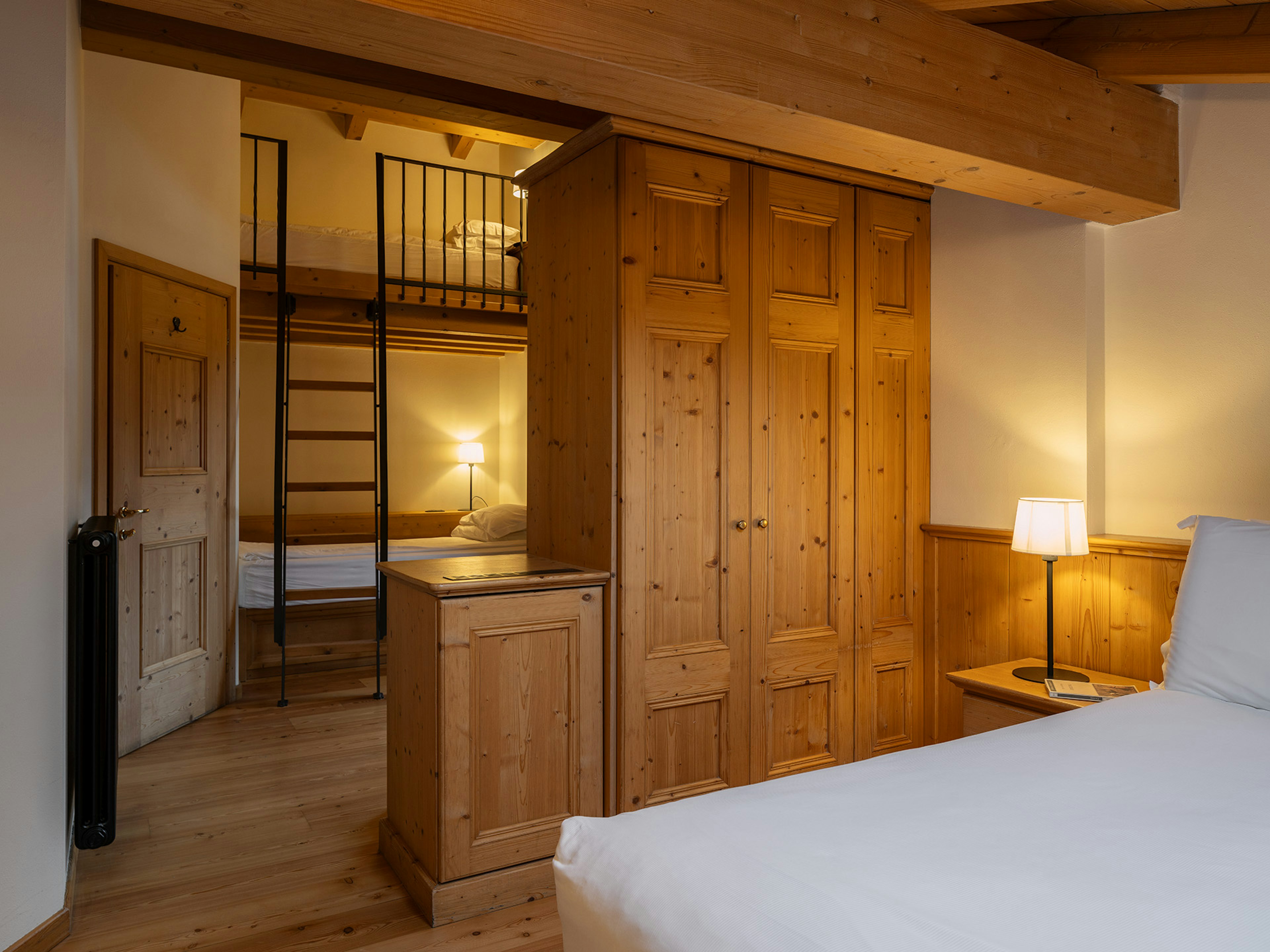 Attico con soffitto in legno, pavimento in abete e letto matrimoniale.