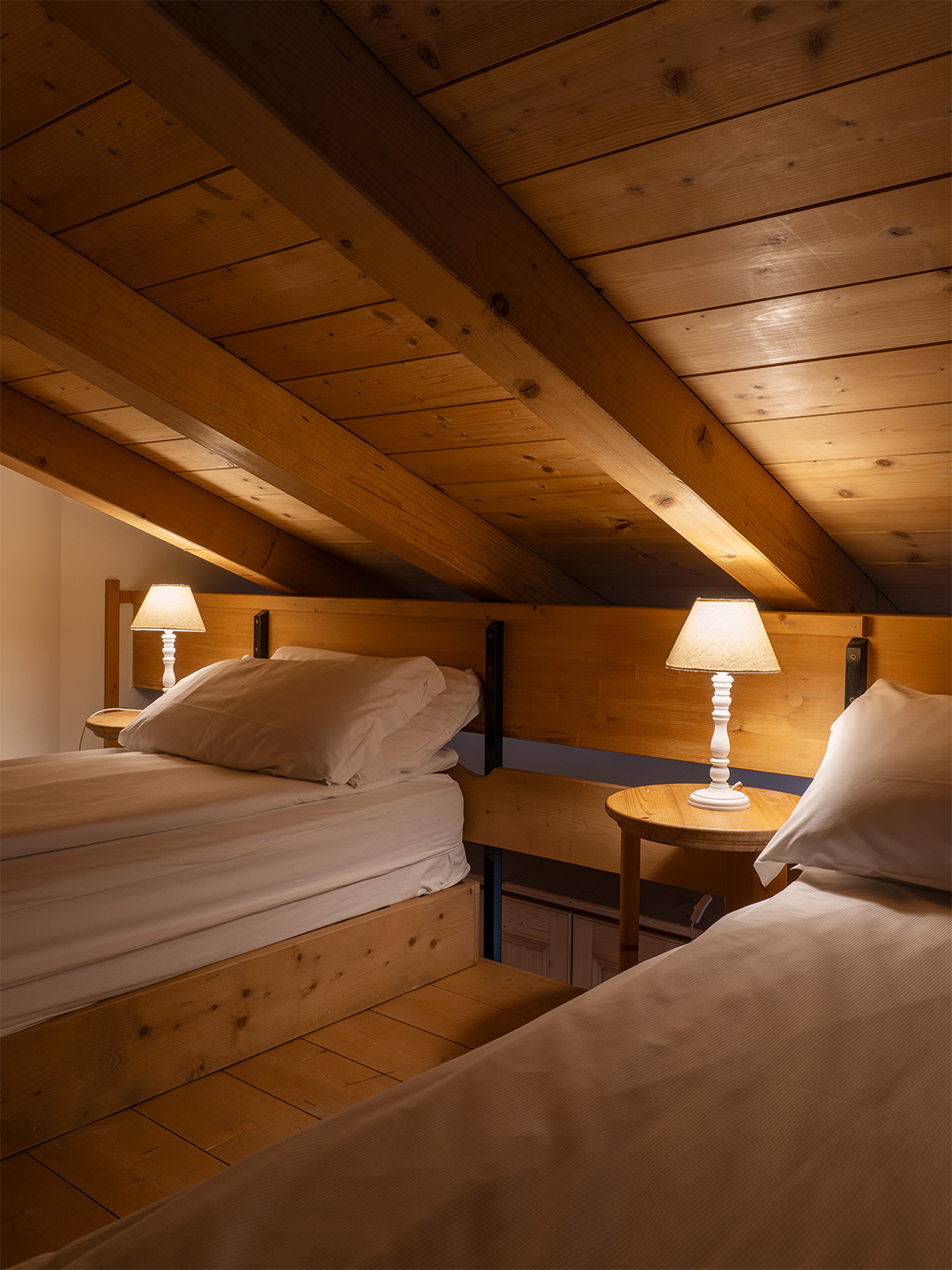 Due letti singoli a soppalco, travi e soffitto in legno.