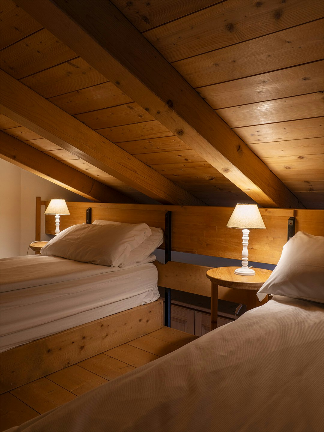 Due letti singoli a soppalco, travi e soffitto in legno.