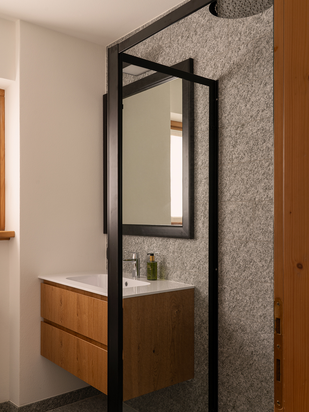 Bagno con grande specchio e doccia rain shower e mobile lavabo in rovere. 