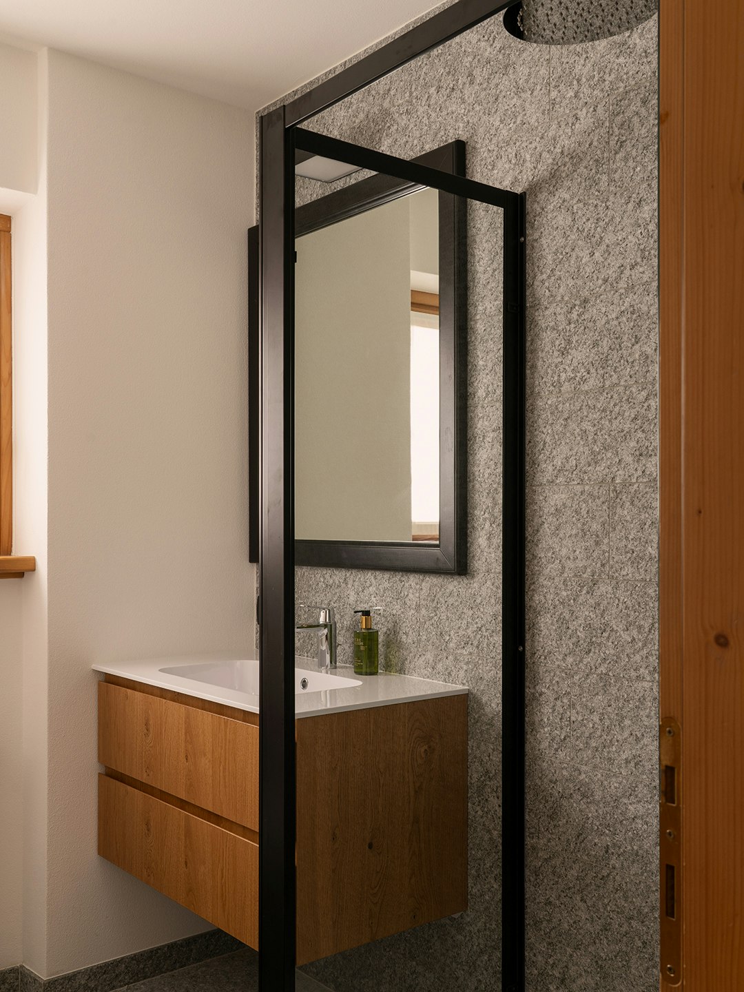 Bagno con grande specchio e doccia rain shower e mobile lavabo in rovere.