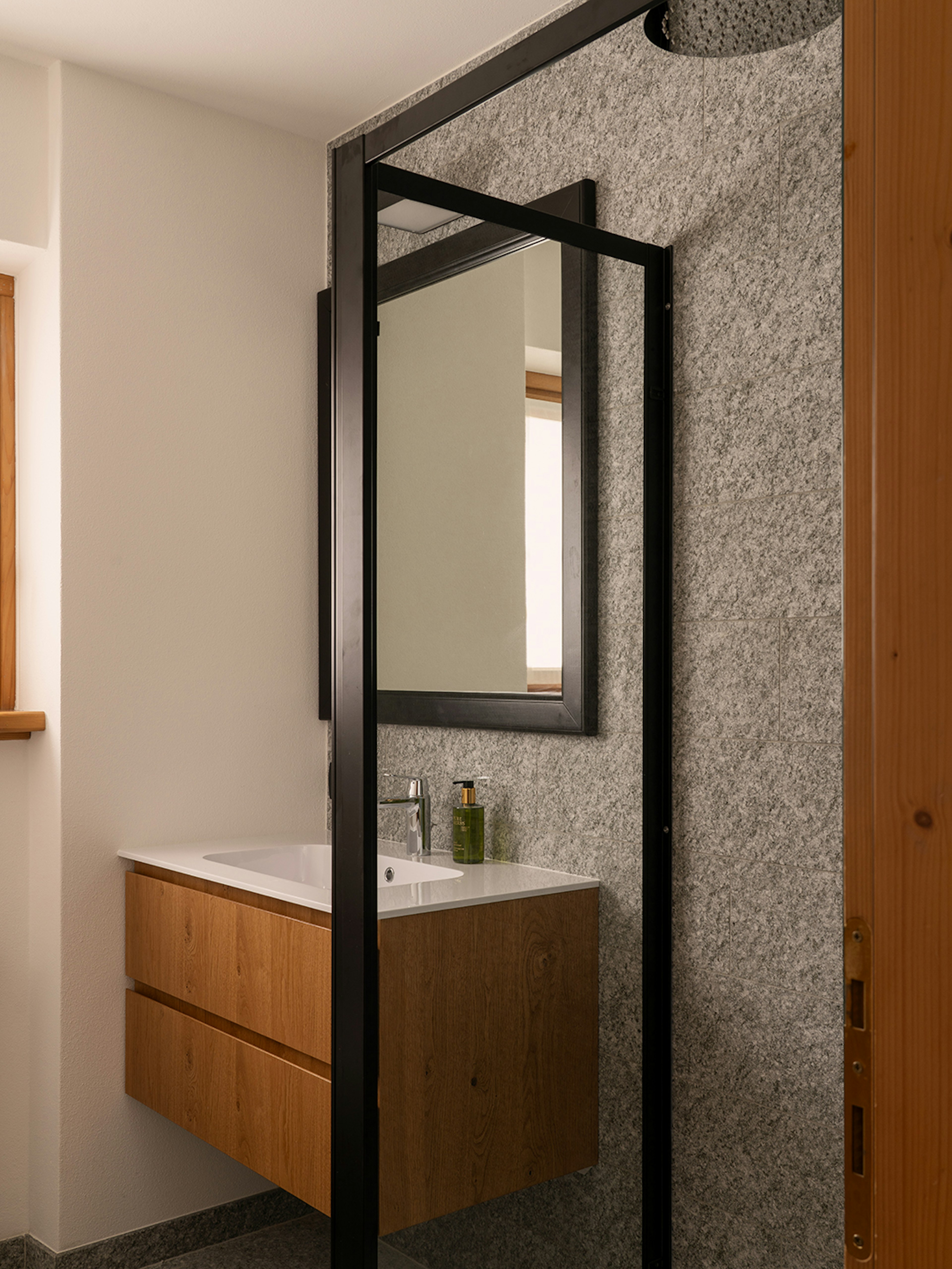 Bagno con grande specchio e doccia rain shower e mobile lavabo in rovere. 
