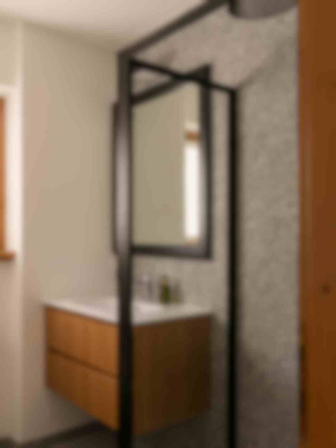 Bagno con grande specchio e doccia rain shower e mobile lavabo in rovere.