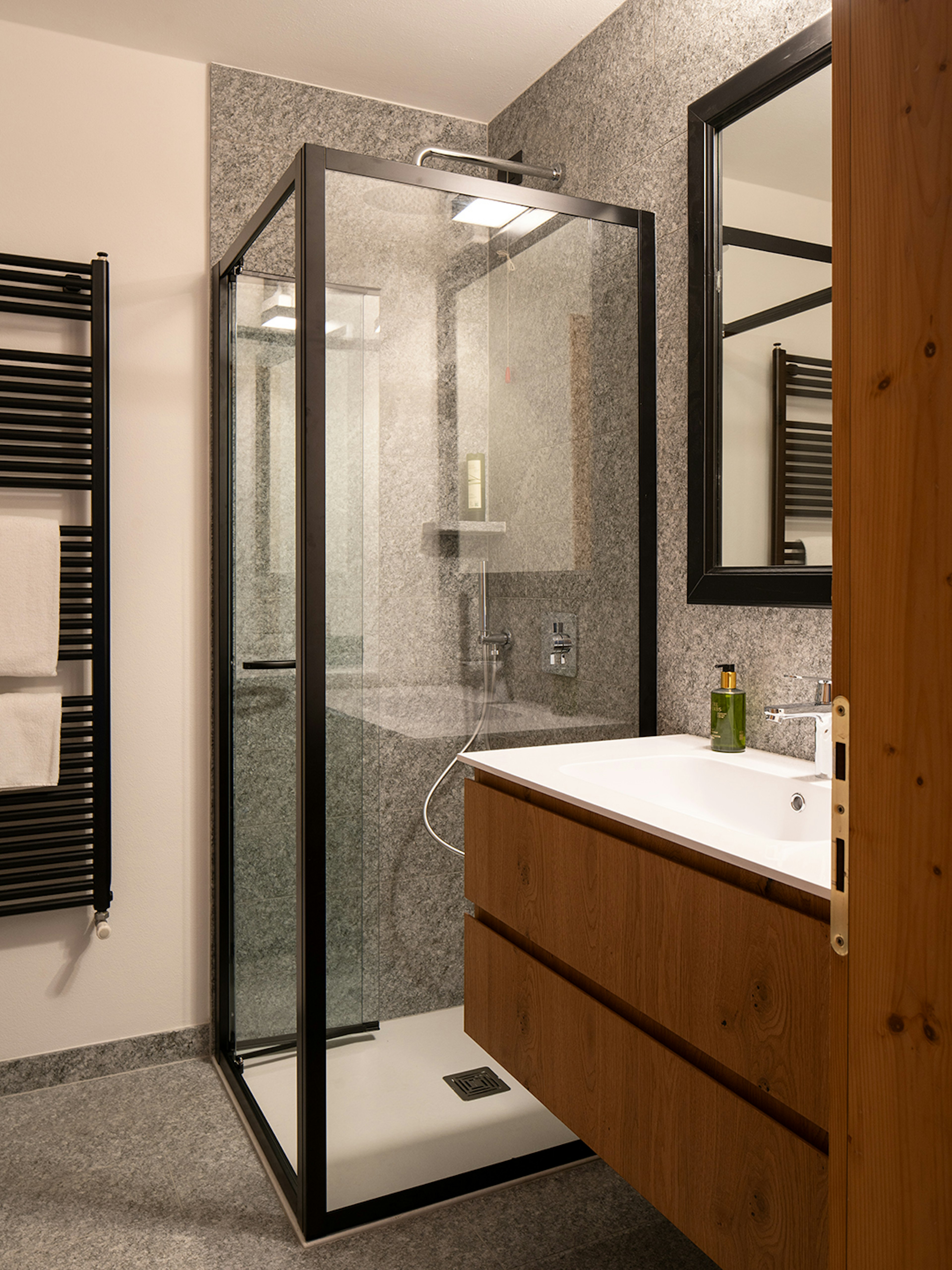 Doccia con rain shower e pietra di Luserna. Mobile lavabo in rovere e grande specchio. 