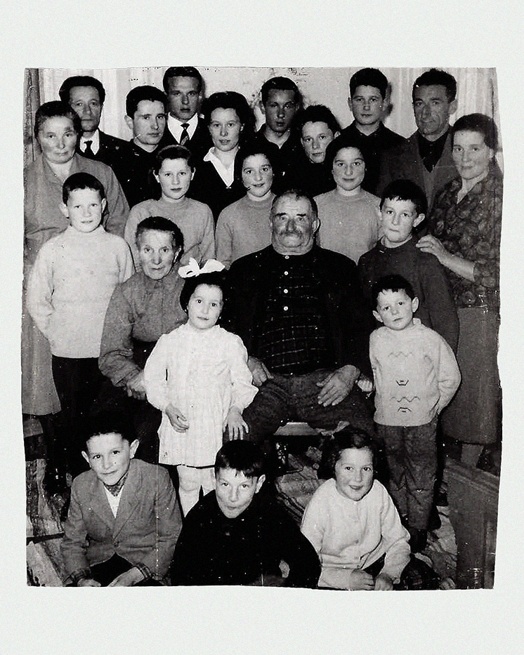 Ritratto di famiglia numerosa in bianco e nero con patriarca al centro, generazioni riunite