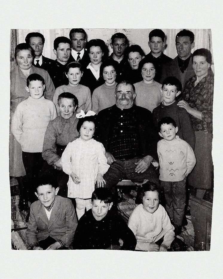 Ritratto di famiglia numerosa in bianco e nero con patriarca al centro, generazioni riunite