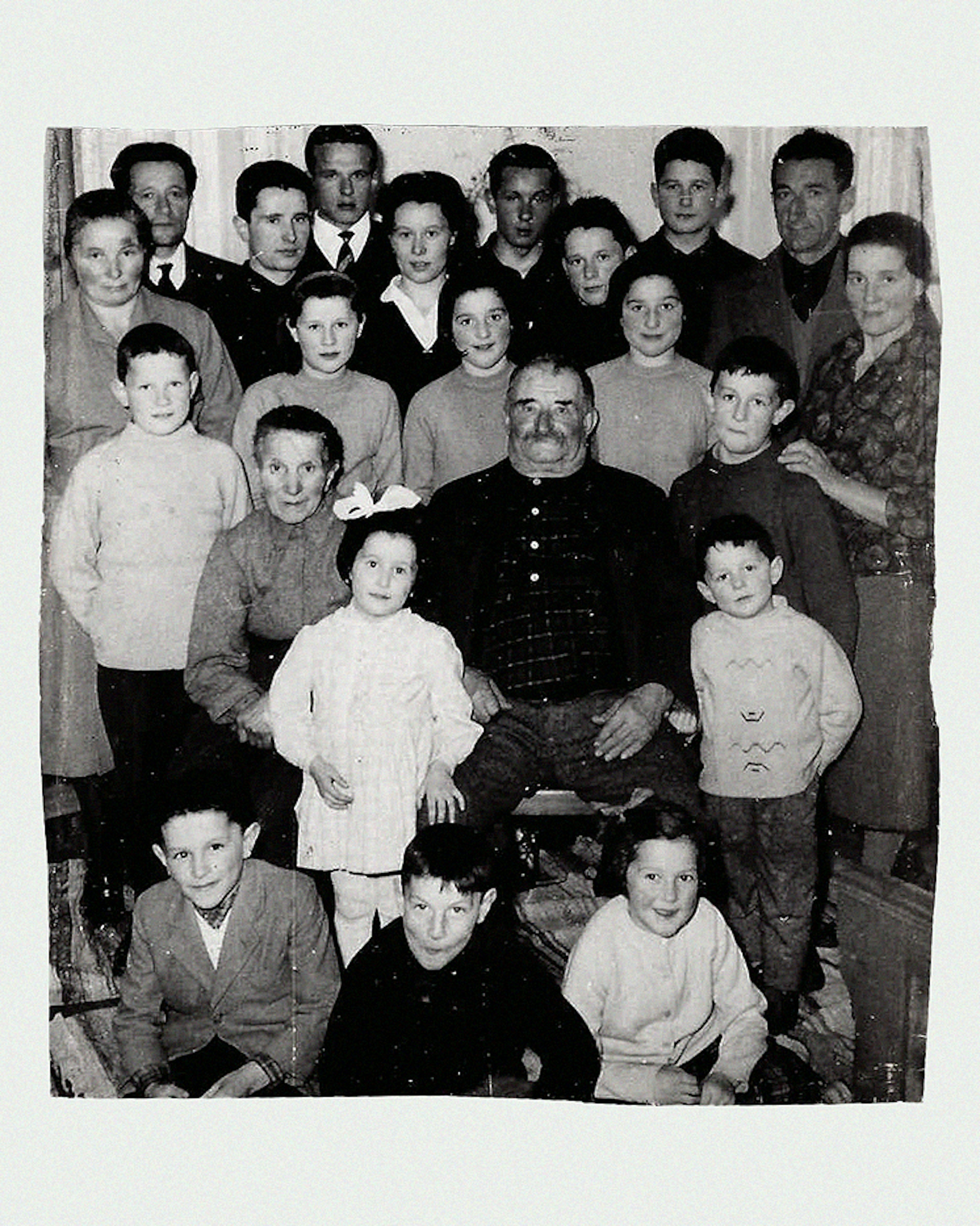 Ritratto di famiglia numerosa in bianco e nero con patriarca al centro, generazioni riunite