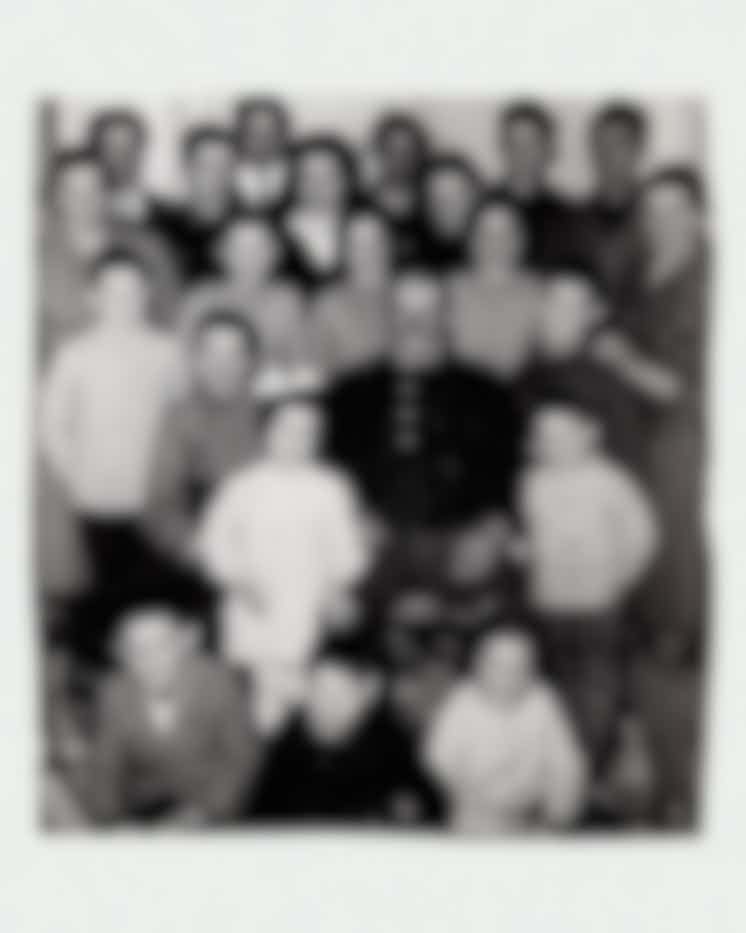 Ritratto di famiglia numerosa in bianco e nero con patriarca al centro, generazioni riunite