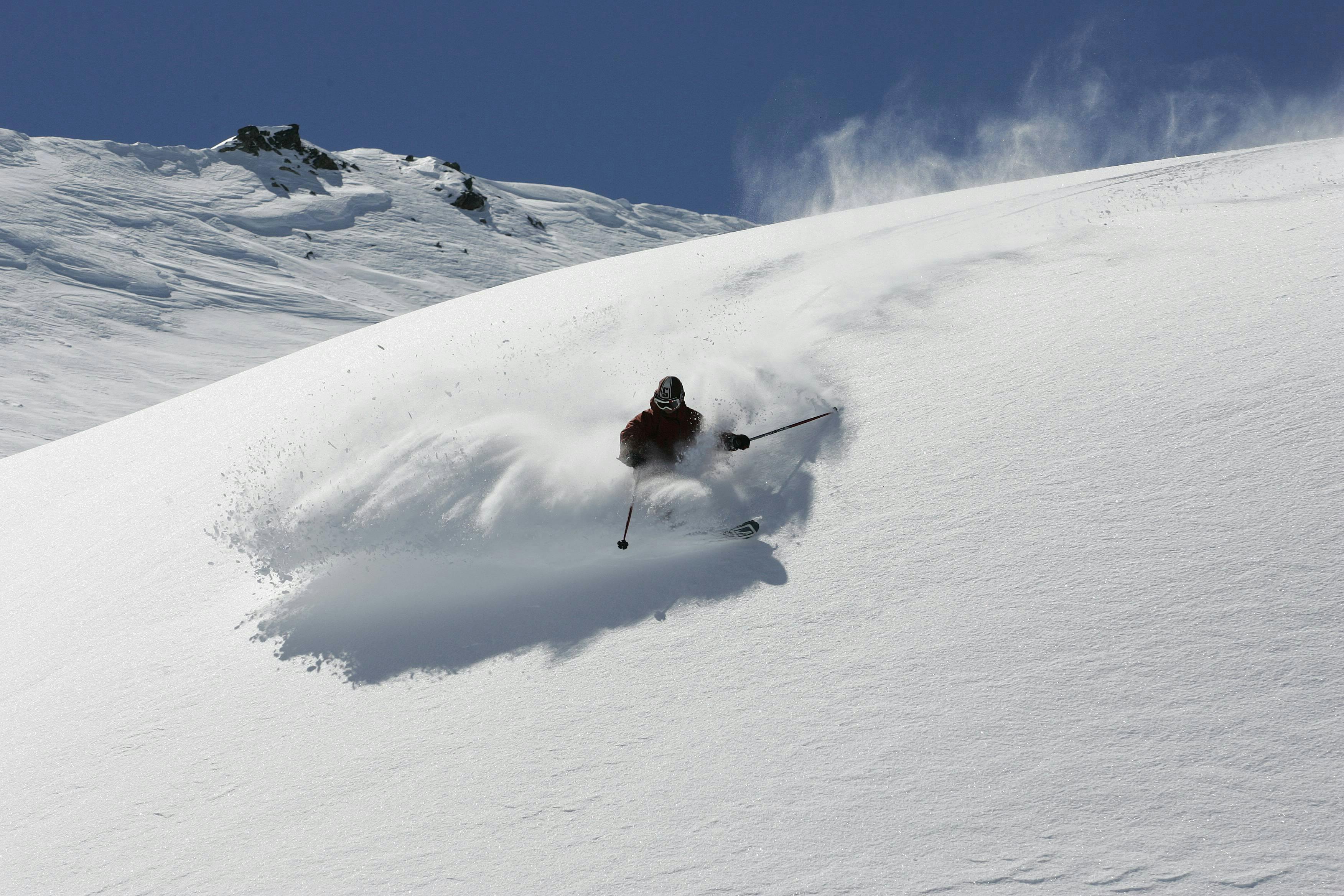 Sciatore freeride in alta quota su neve fresca.