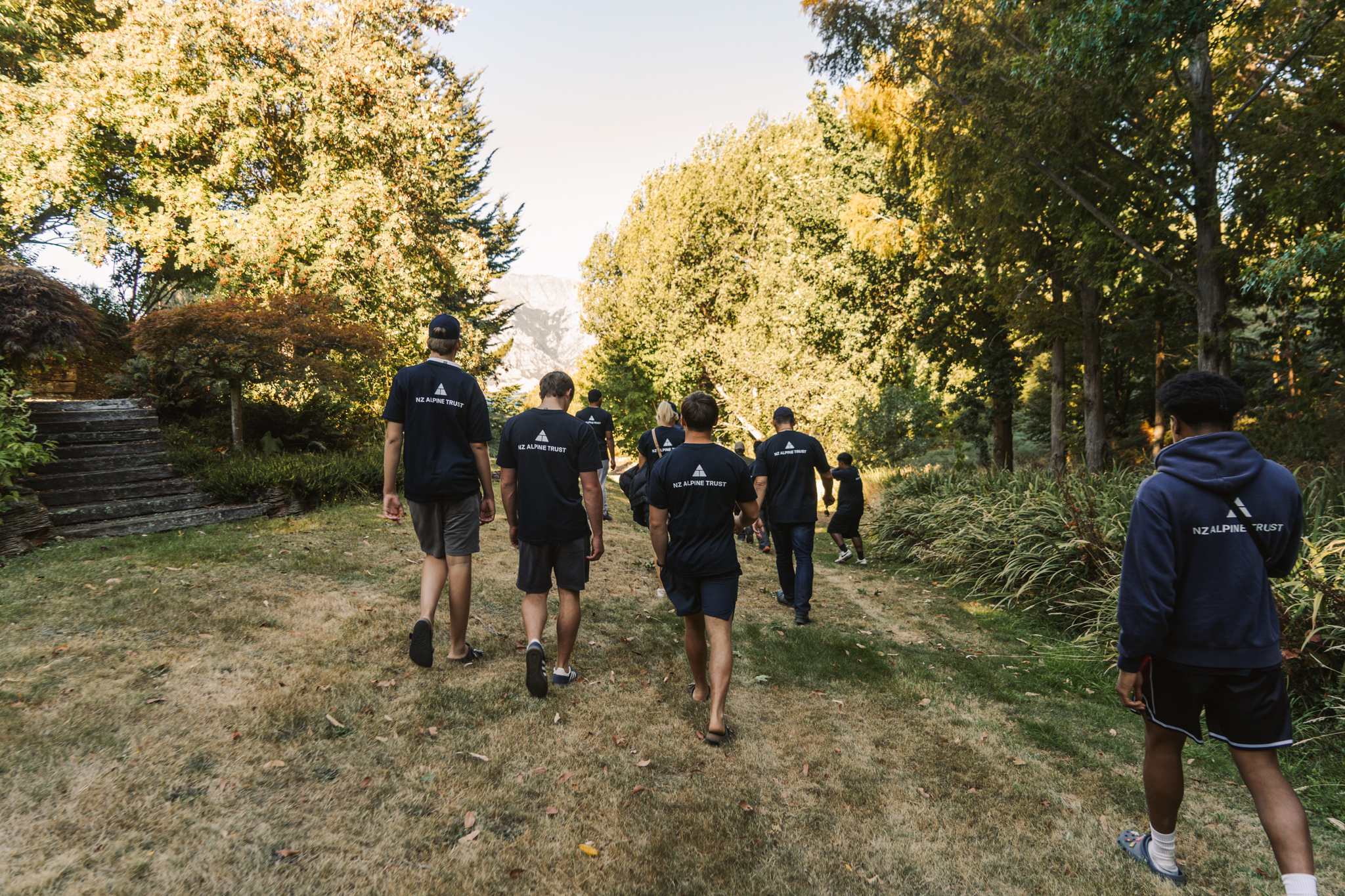 A group of people walking along a path surrounded by trees