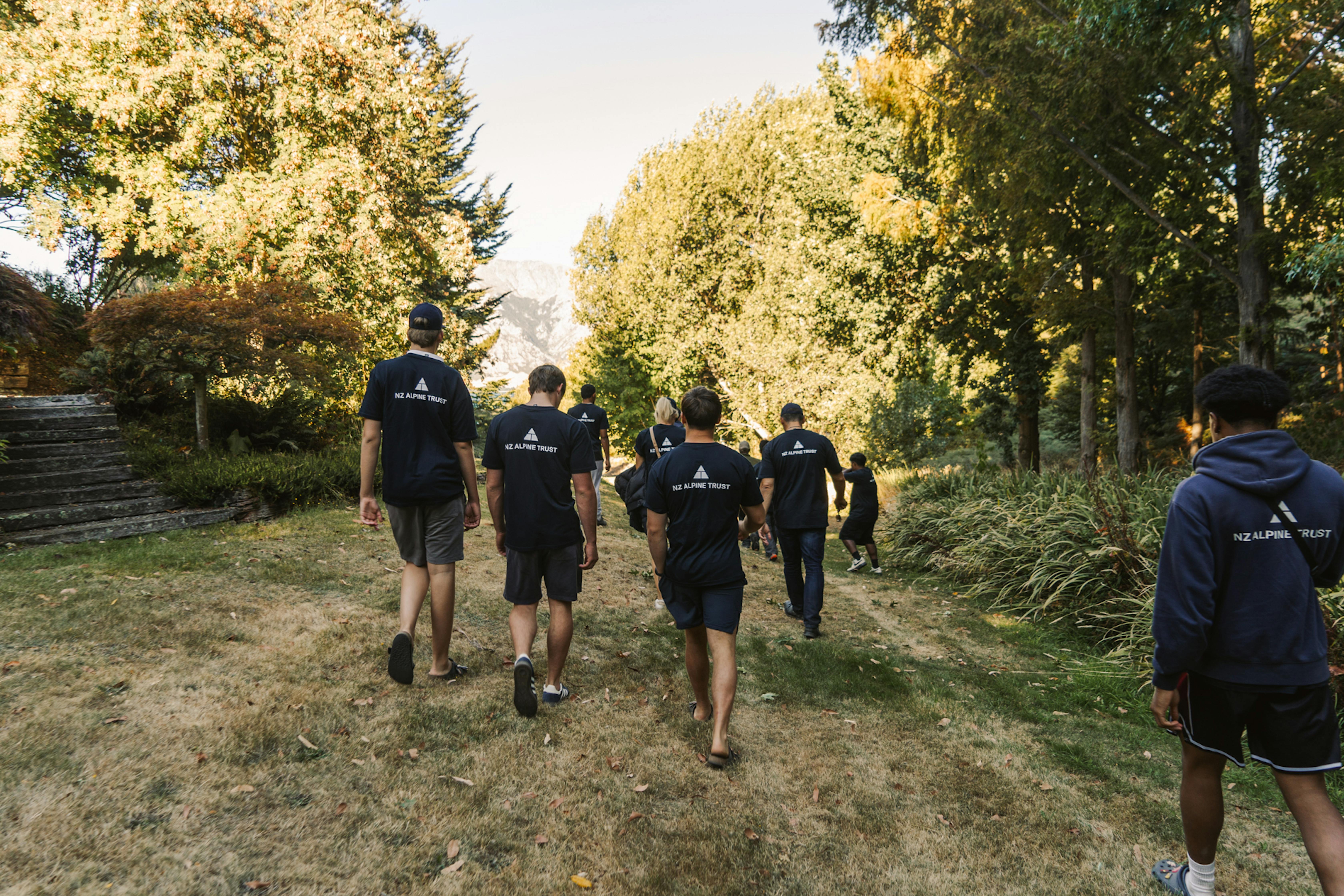 A group of people walking along a path surrounded by trees