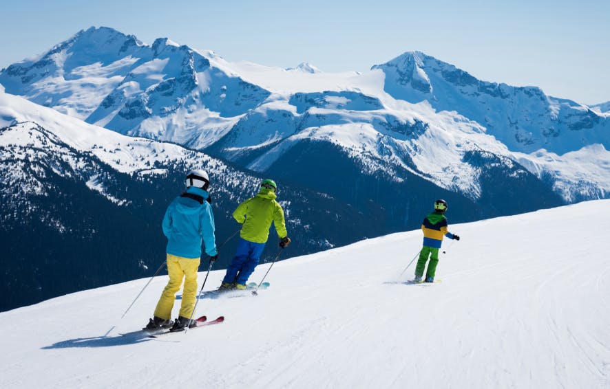 alt= three skiers with blue and green jacketsin the southern alps of New Zealand