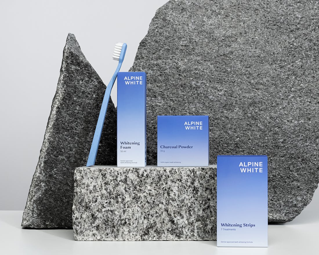 Pack Blanchiment Alpine White avec poudre au charbon actif, bandes blanchissantes et mousse blanchissante. Routine complète pour un sourire visiblement plus blanc à la maison.