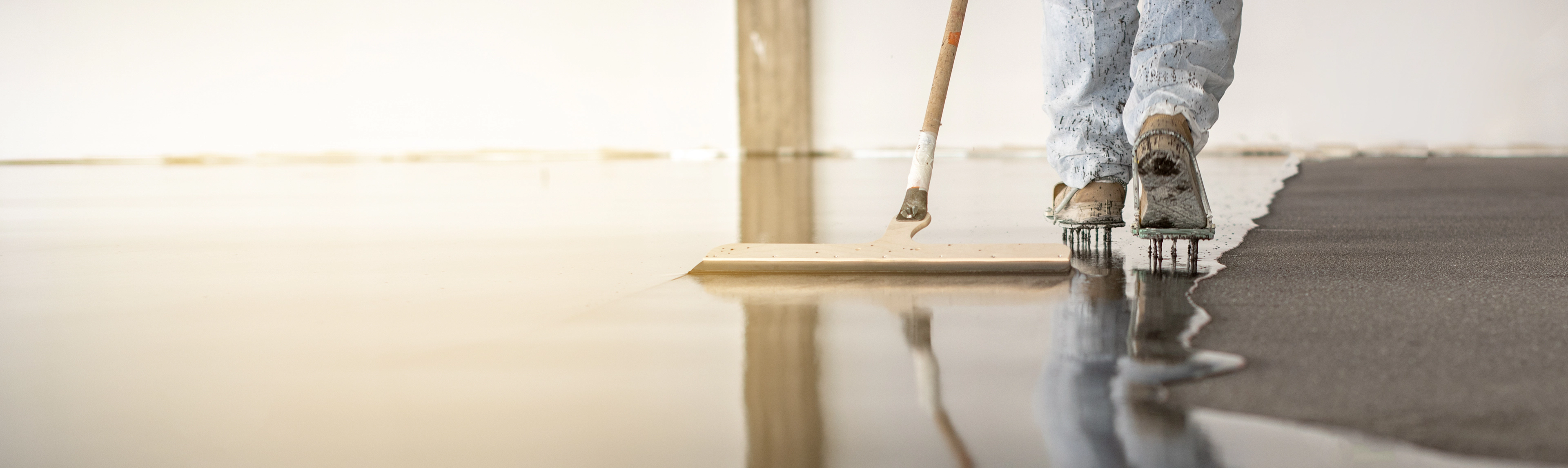 Applicator laying a seamless resin floor, wet finish reflecting the light.