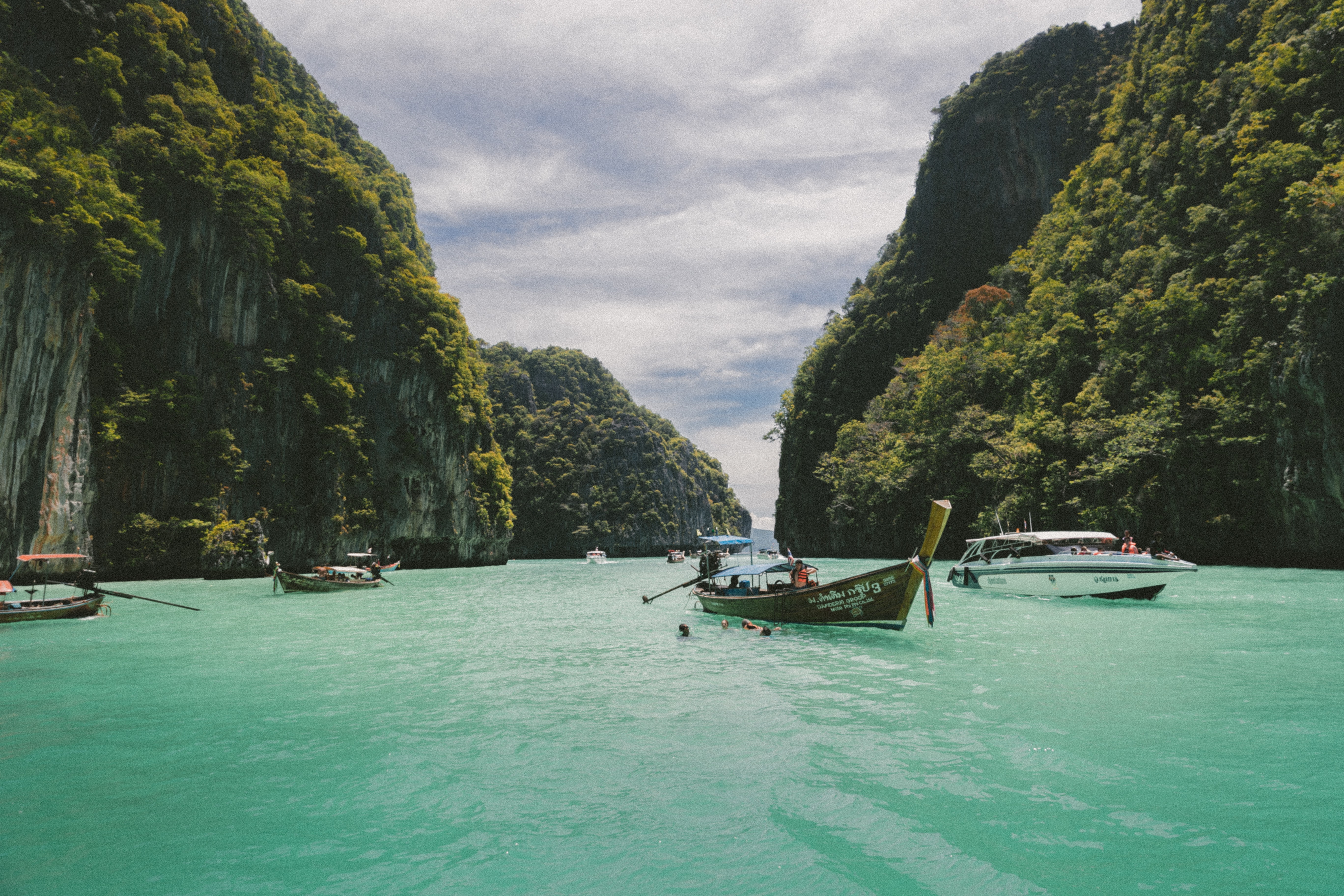 The blue waters of the Vietnamese sea surrounded by green mountains with boats bobbing about 