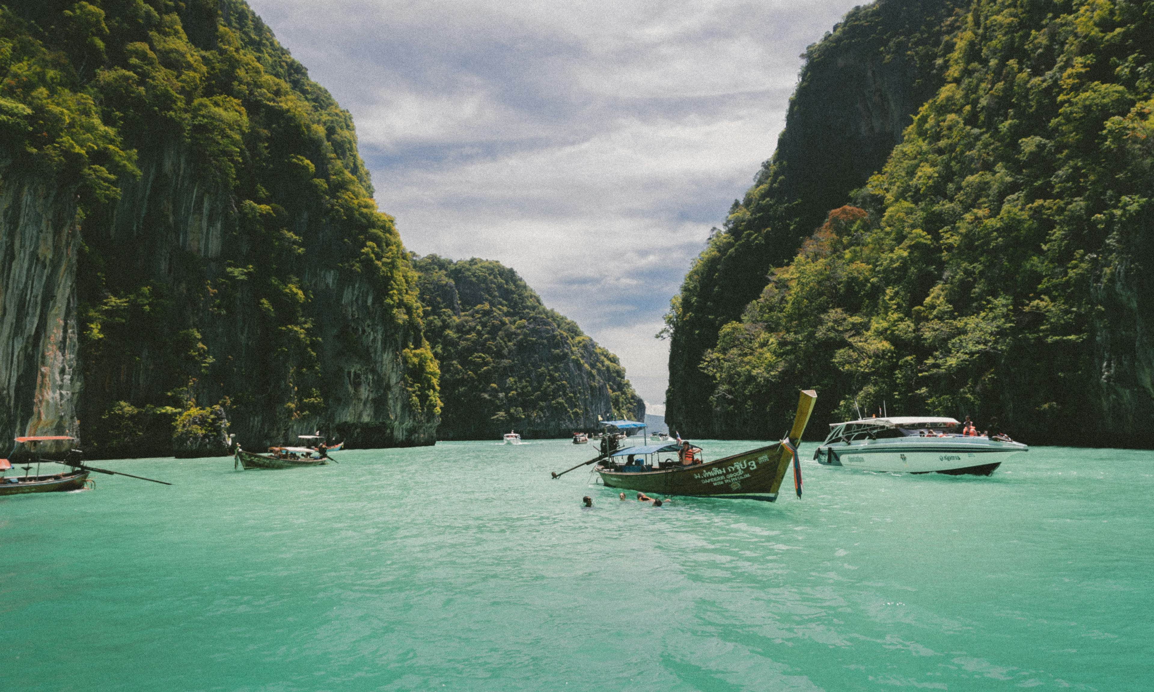 The blue waters of the Vietnamese sea surrounded by green mountains with boats bobbing about 