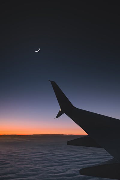 View of airplane wing with sunset outside the plane window