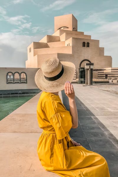 Women in yellow dress in front of the Museum of Islamic Art, Doha, Qatar