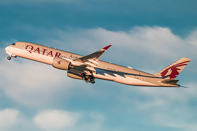 A Qatar Airways A350 taking off into the sunset