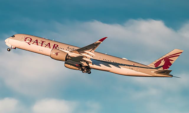 A Qatar Airways A350 taking off into the sunset