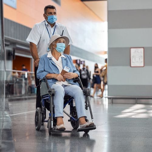 Elderly woman being assisted at the airport in a wheelchair