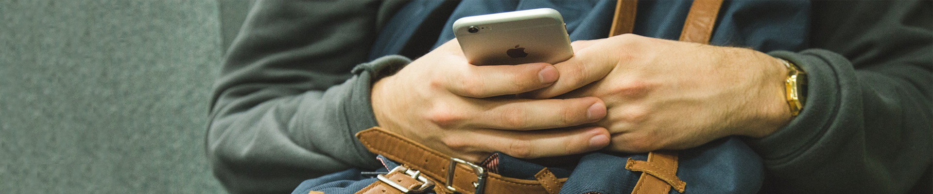 person with a phone in the hand and resting on top of a backpack
