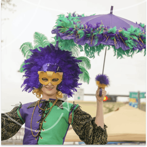 Lady dressed in full Mardi Gras outfit with decorated umbrella at a festival.