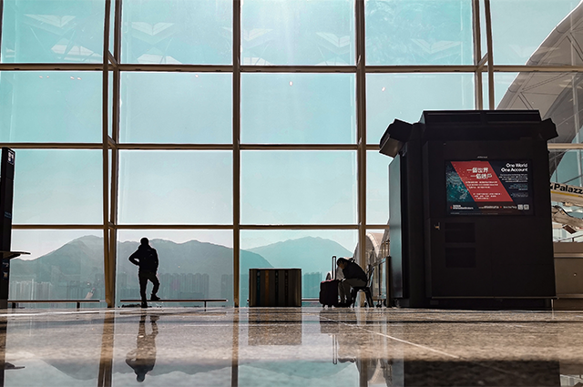 Hong Kong International Airport terminal with a passenger looking out to the city in the distance