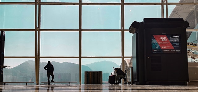 Hong Kong International Airport terminal with a passenger looking out to the city in the distance