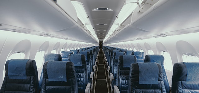 Cabin onboard an aircraft with leather seats and white fixtures