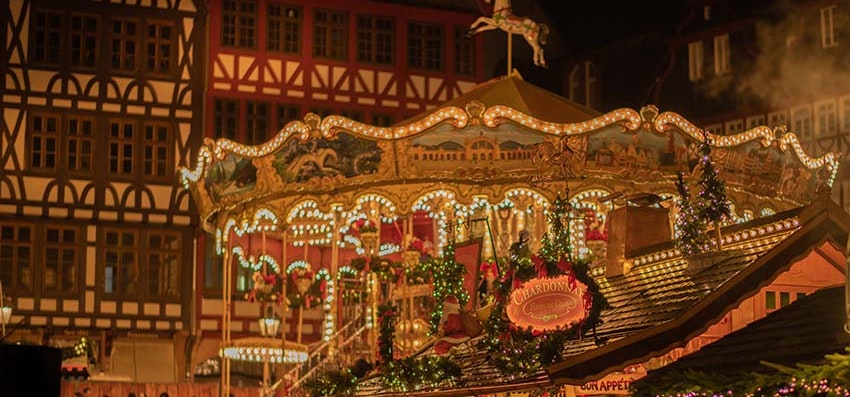 A picture of a carousel at a Christmas market during the night. 