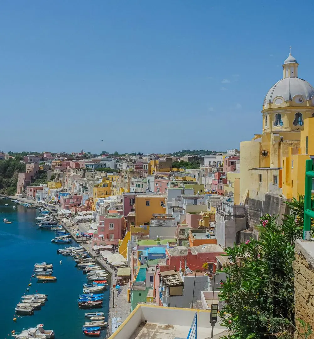 Group of colourful buildings next to a port with blue water and boats during the summer in Amalfi Coast Italy