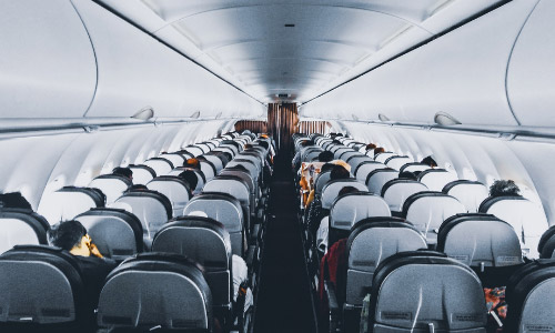 A shot looking down the aisle on a plane with passengers seated in a 3-3 formation on either side