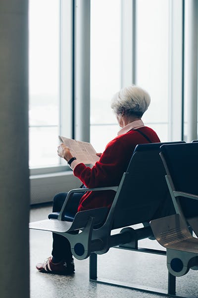 Picture of an elderly woman sitting in an airport terminal on her own
