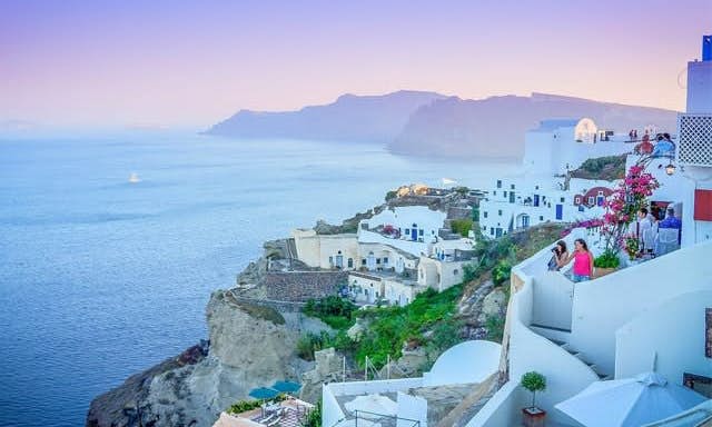 White buildings climb up the mountainous cliffs of Oia with the blue seas below 