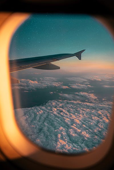 View outside airplane window with sunset and airplane wing