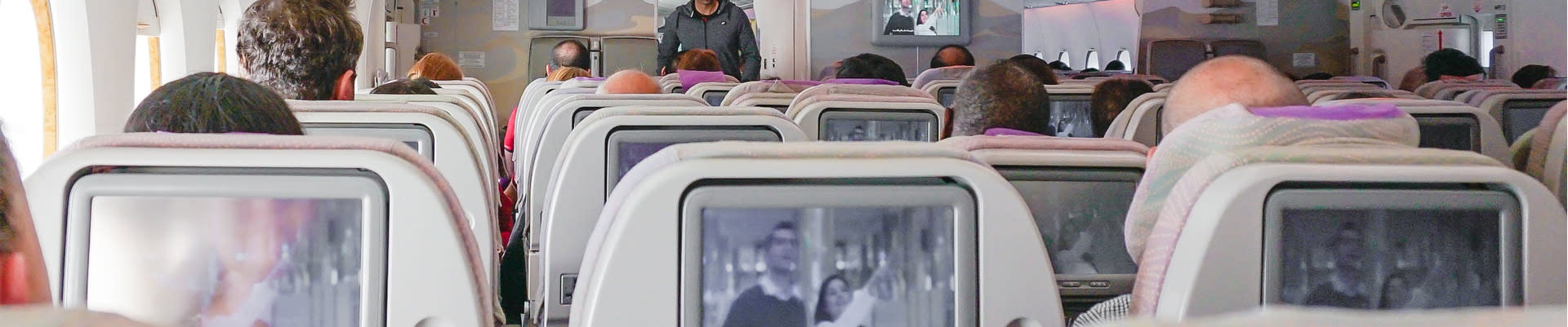 Seats on airplane with tv screen on each seat