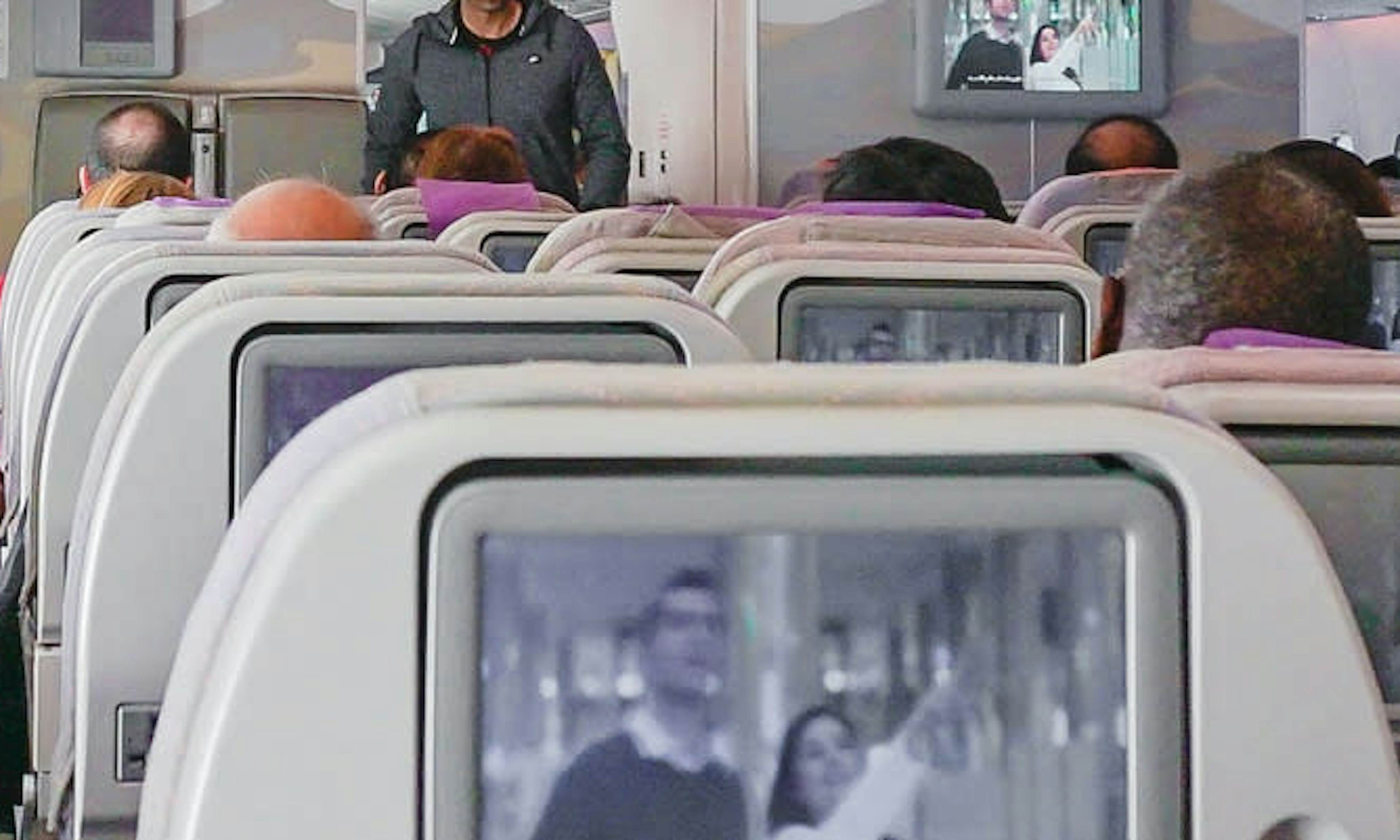 Seats on airplane with tv screen on each seat