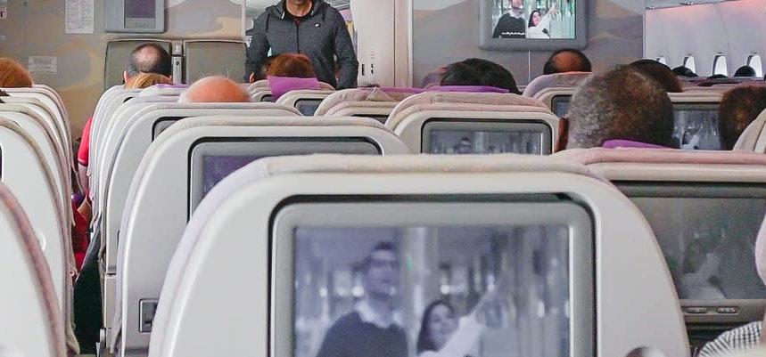 Seats on airplane with tv screen on each seat