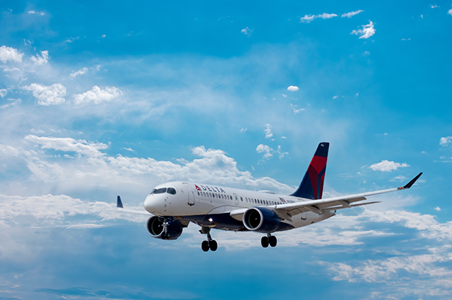 Delta A220 aircraft beginning its decent from the blue skies 