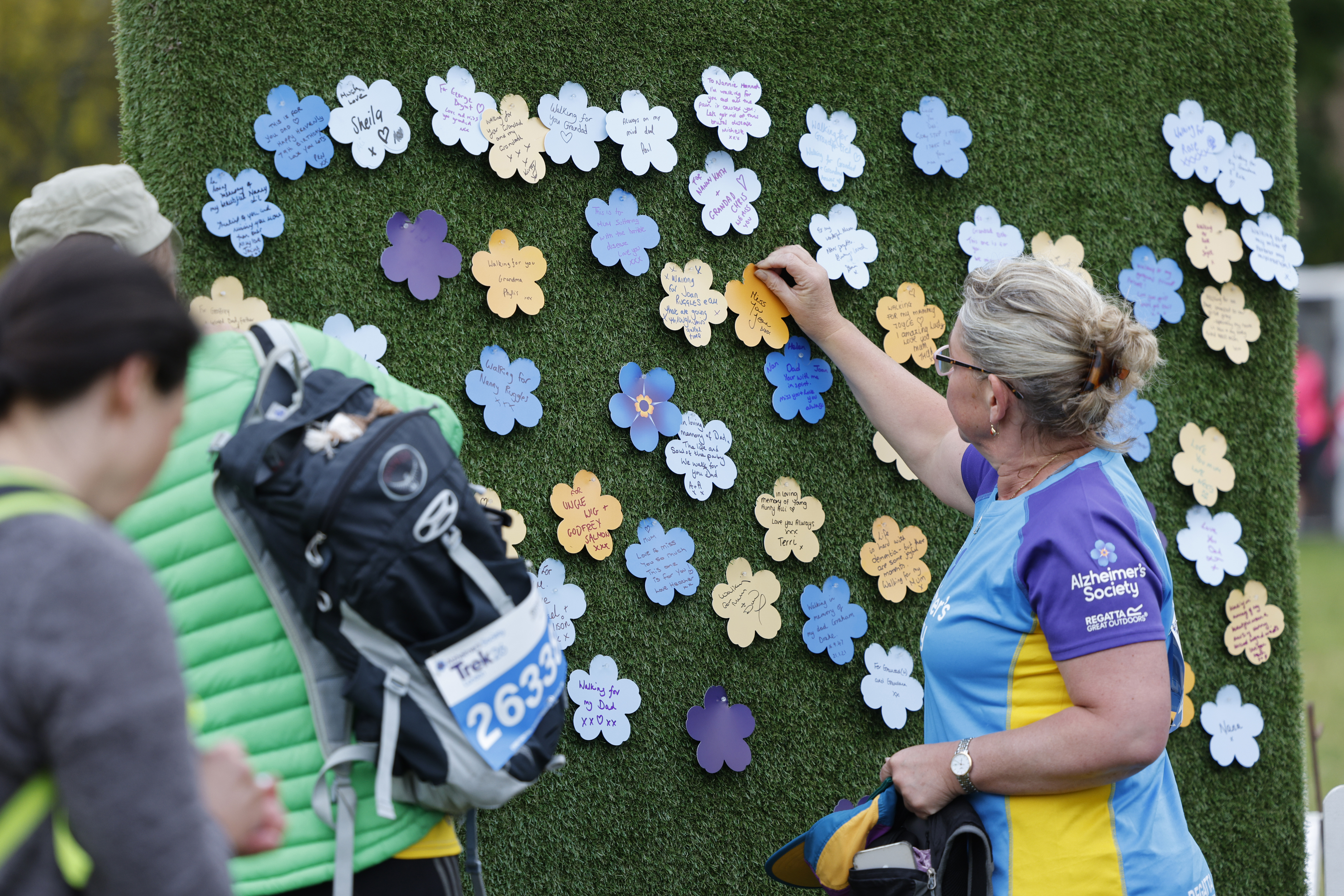 Trek26 participant pinning a paper flower onto the forget me not garden wall.