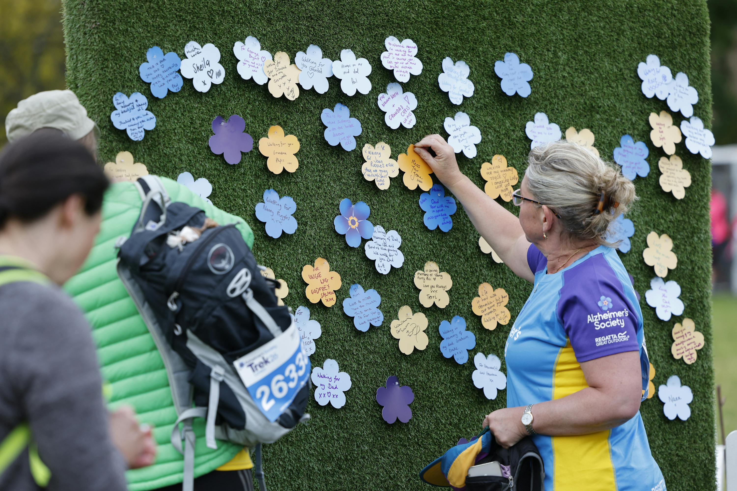 Trek26 participant pinning a paper flower onto the forget me not garden wall.