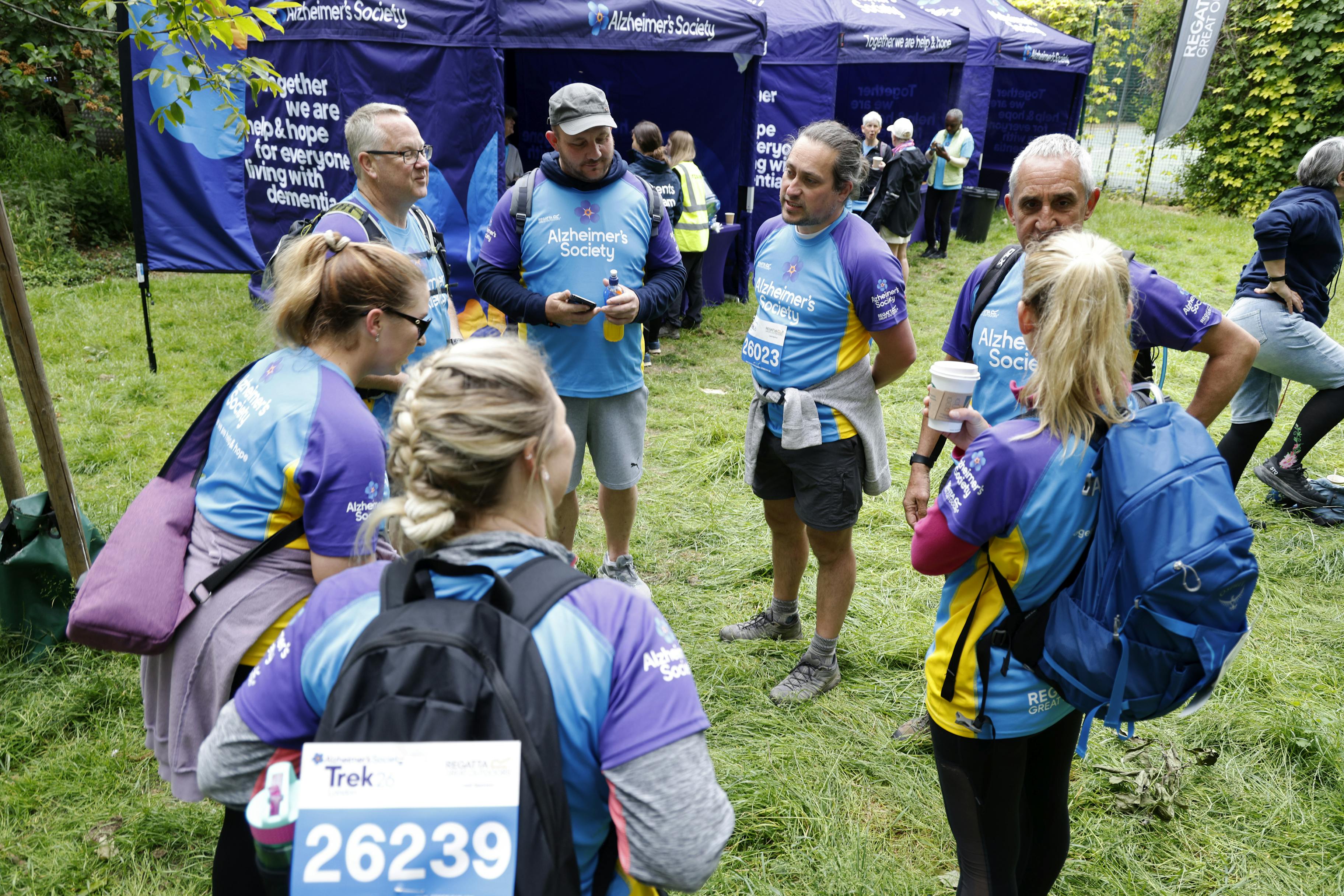 Group of seven Trek26 participants standing in a circle at a rest stop.