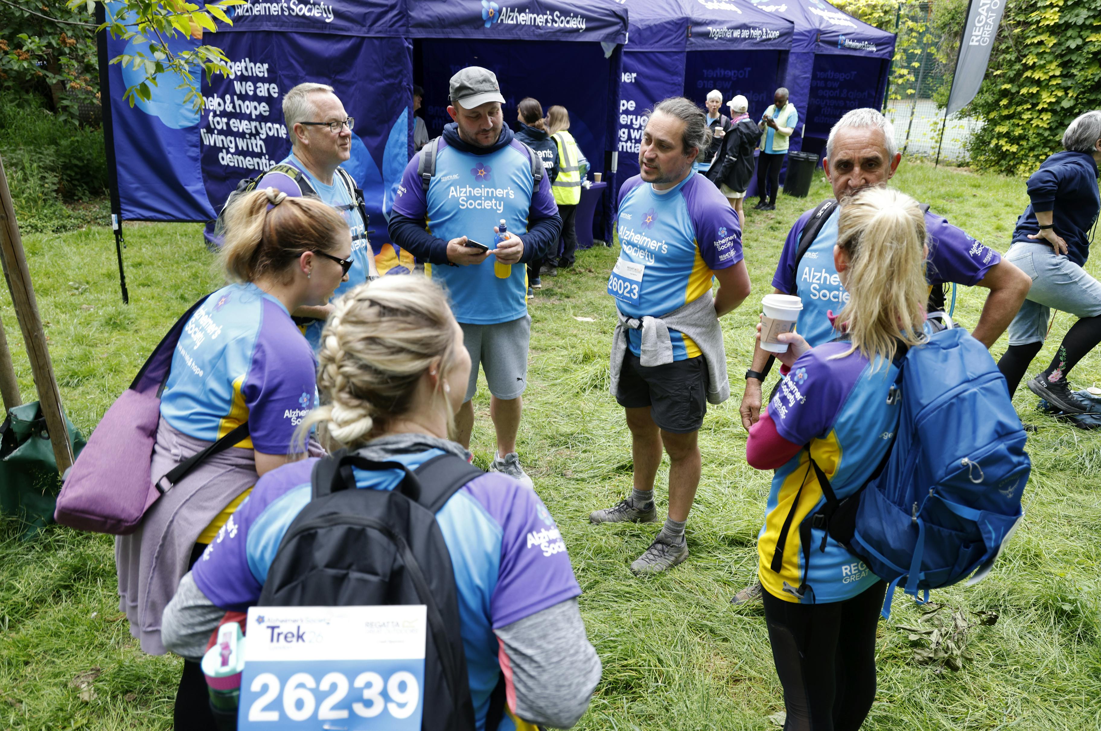 Group of seven Trek26 participants standing in a circle at a rest stop.