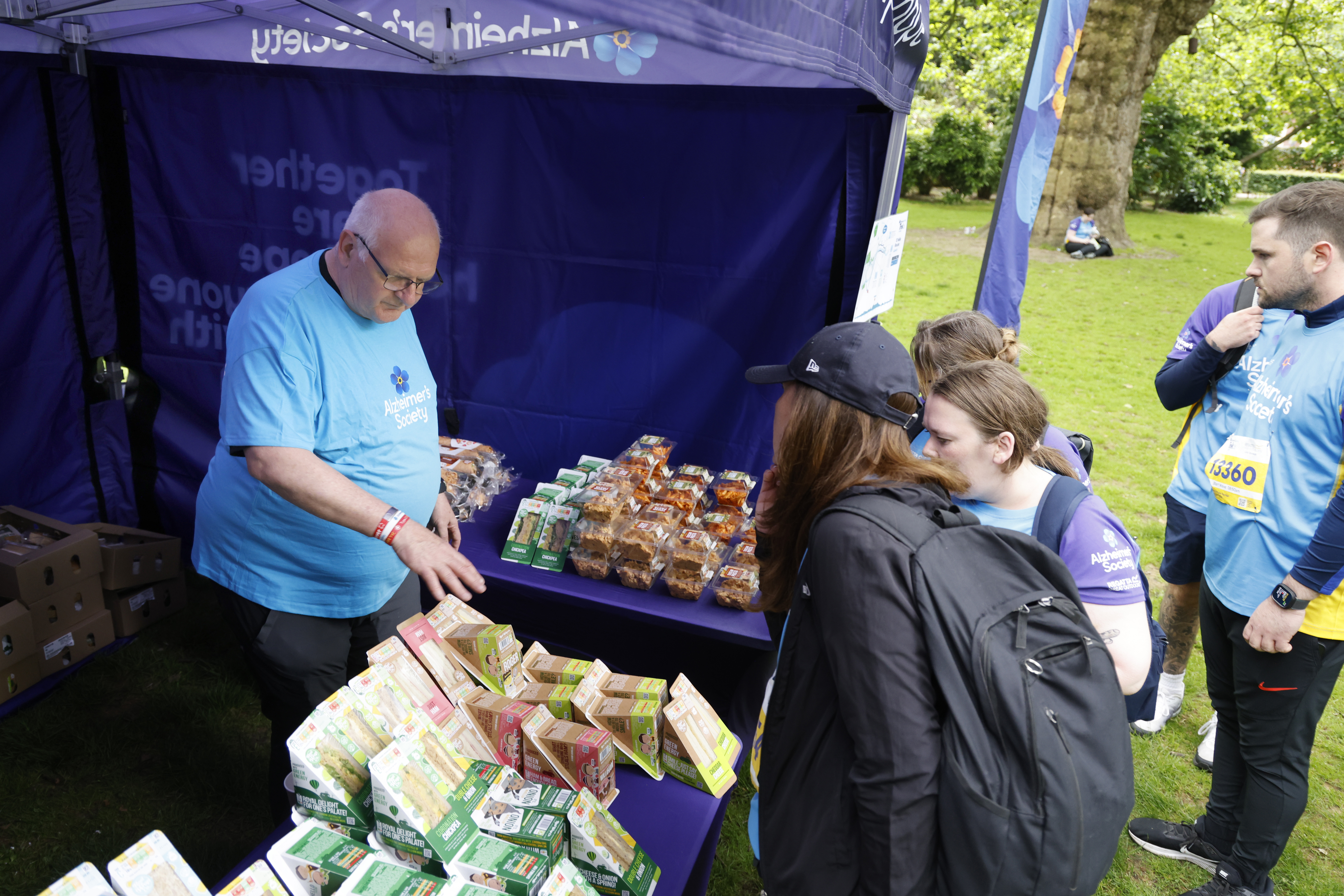 Trek26 volunteer standing behind a table with sandwiches and snacks.