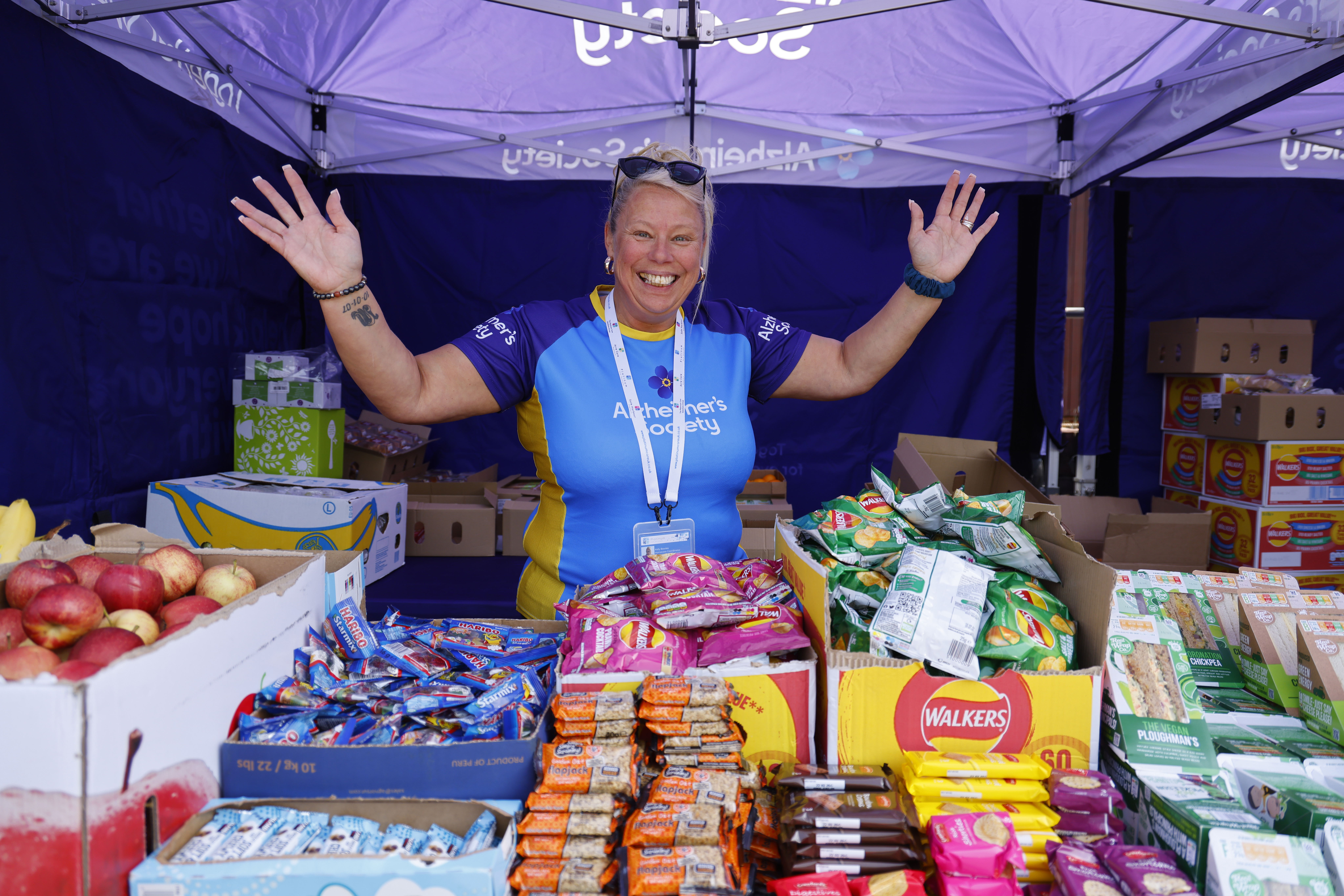 Trek26 volunteer standing behind a snack table, smiling.
